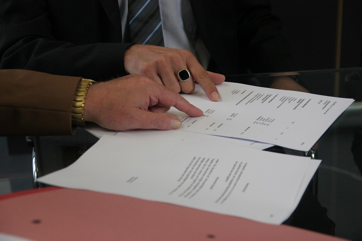 Mains signant un document contractuel sur un bureau